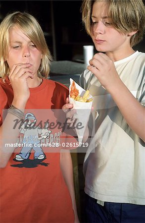 Two Boys eating Chips out of a little Paperbag - Takeaway - Nutrition - Youth