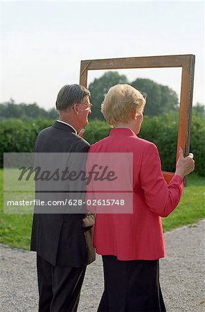 Someone taking a Picture of an old married Couple through a Frame - Festivity - Family Party - Garden