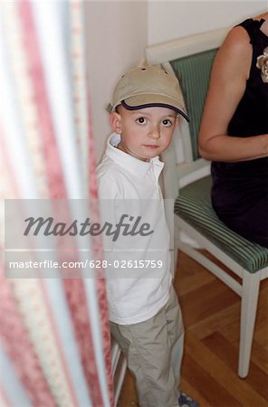 Little Boy with a Cap standing next to a Curtain - Childhood - Look