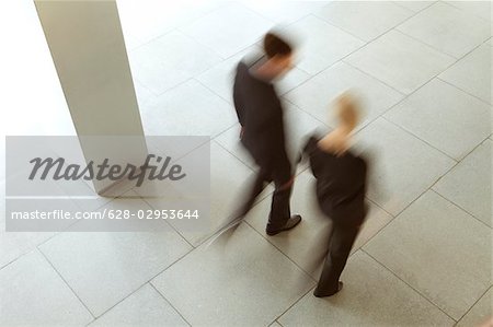 Businessman and businesswoman walking in lobby, Munich, Bavaria, Germany