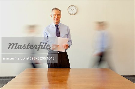 Businessman holding papers with people in background passing by, Munich, Bavaria, Germany
