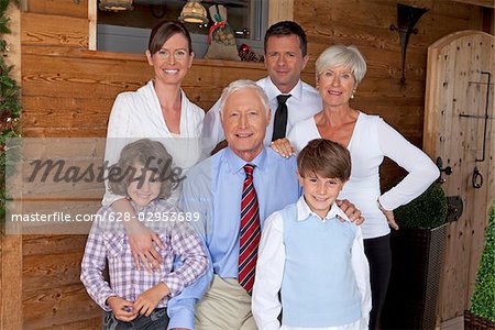 Grandparents, parents and children in front of wooden house