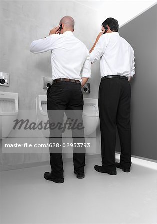 Two businessmen at urinal with cell phones