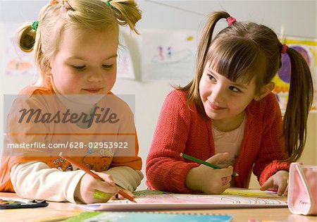 Two girls drawing with color pencils