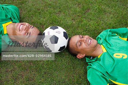 Two Brazilian soccer players lying on grass