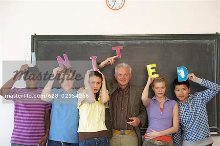 Students and professor in front of a blackboard holding letters