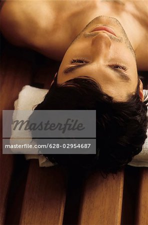 Darkhaired Man with a Towel under his Head - Bench - Sauna - Relaxation - Wellness