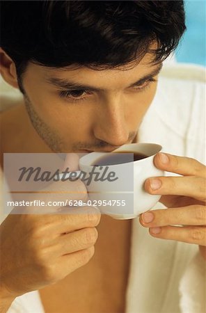 Darkhaired Man in a Bathrobe drinking from a Coffee-Cup - Look - Hot Beverage - Leisure Time