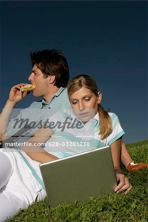Young couple with laptop in grass