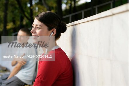 Young girl listening music about earphones, boy in background