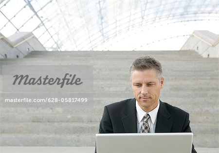 Businessman sitting on stairs, using laptop