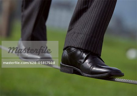 Businessman balancing on a high wire (part of), close-up, selective focus