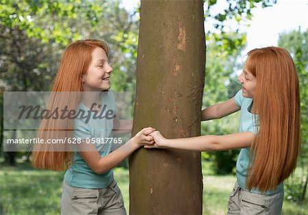 Two Red Headed Sisters Sharing A Rope Tree Swing by Stocksy