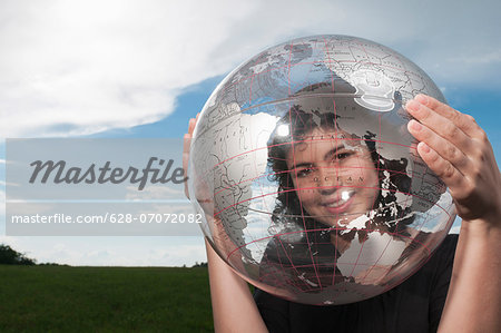 Girl looking through transparent globe outdoors