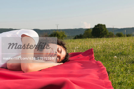 Girl sleeping on blanket in meadow