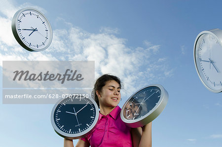 Girl holding clocks outdoors