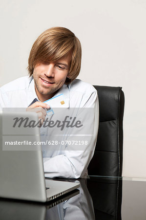 Man with laptop holding credit card