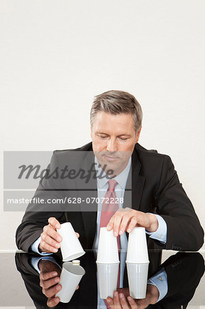 Businessman playing shell game with plastic cups at desk