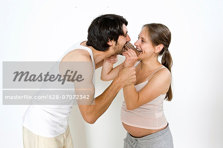 Happy man and pregnant woman eating chocolate Happy man and pregnant woman eating chocolate