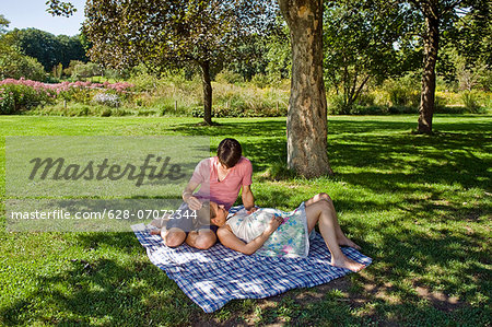 Man and pregnant woman on a blanket in a park