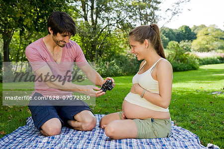 Man taking photograph of pregnant woman in a park