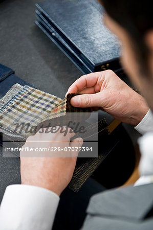 Man in a tailor studio looking at fabric swatches