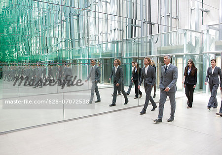 Businesspeople walking along mirror wall