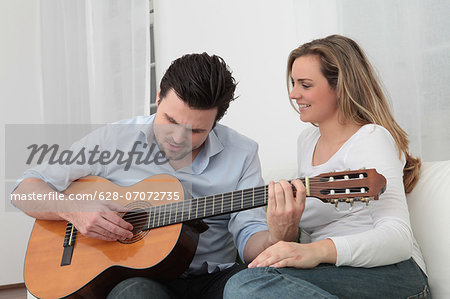 Man playing guitar to woman on couch