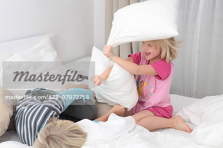Brother and sister having a pillow fight in bed Brother and sister having a pillow fight in bed