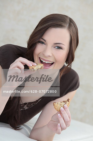 Brunette young woman eating a cookie