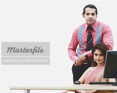 Portrait of a businesswoman sitting with a businessman standing beside her in an office