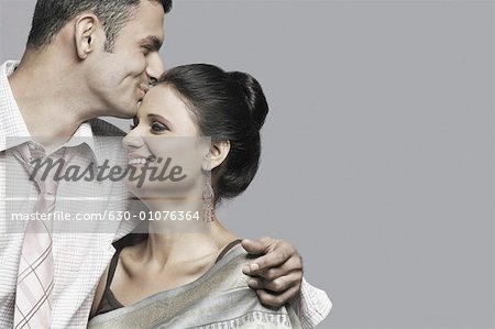 Close-up of a young man kissing a young woman's forehead
