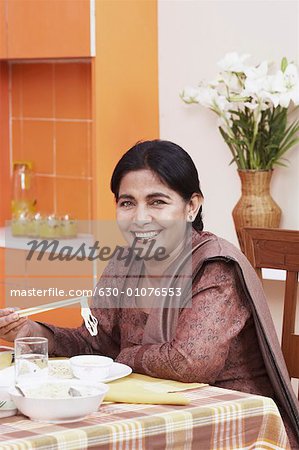 Portrait of a mature woman eating noodles with chopsticks