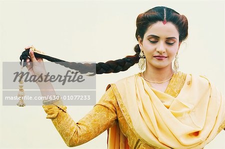 Close-up of a young woman holding her plait with her eyes closed