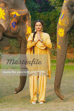 Young woman greeting in front of two elephants