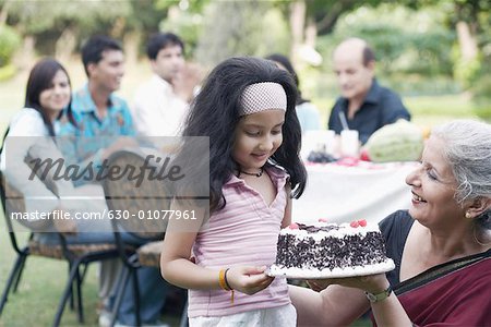 Mature woman and a girl holding a cake