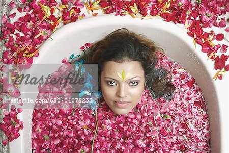 High angle view of a young woman lying in a bathtub with flower petals floating