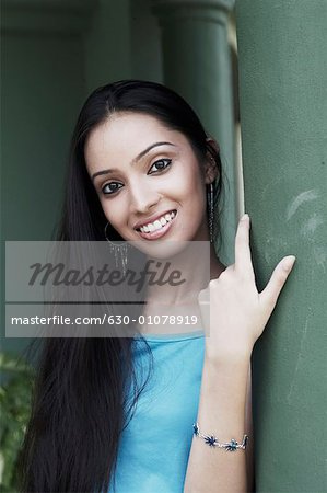 Portrait of a teenage girl leaning against a column smiling