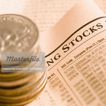 High angle view of a stack of antique coins on a financial newspaper