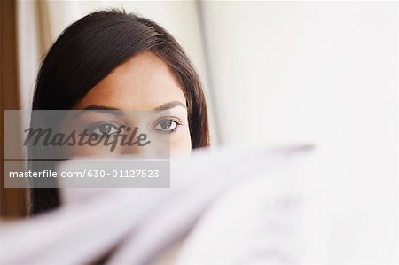 Close-up of a young woman reading a newspaper