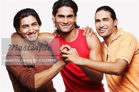 Portrait of three young men holding hands and smiling