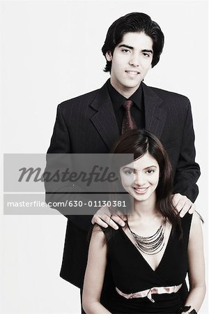 Portrait of a young man standing behind a young woman with his hands on her shoulders