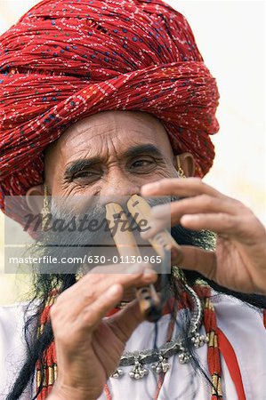 Portrait of a mature man playing two flutes with his nose, Jaipur, Rajasthan, India