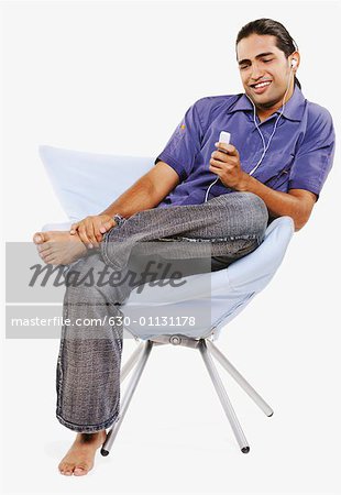 Young man sitting on a chair and listening to an MP3 player