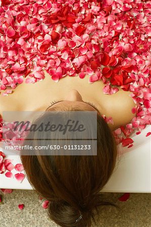 High angle view of a young woman reclining in a bathtub full of rose petals