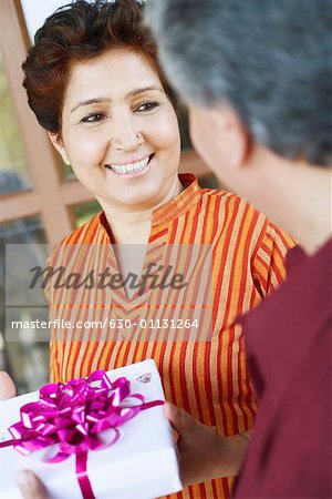 Close-up of a mature man giving a birthday present to a mature woman