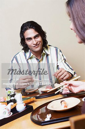 Close-up of a young couple sitting at a dining table and looking at each other