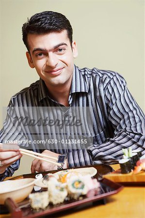 Portrait of a young man sitting at the dining table and smirking