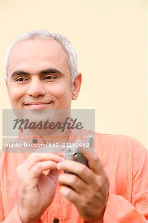 Close-up of a mid adult man holding a mobile phone and smiling