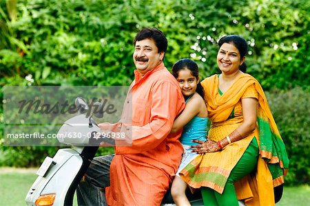 Portrait of a mature man with his wife and daughter riding a motor scooter